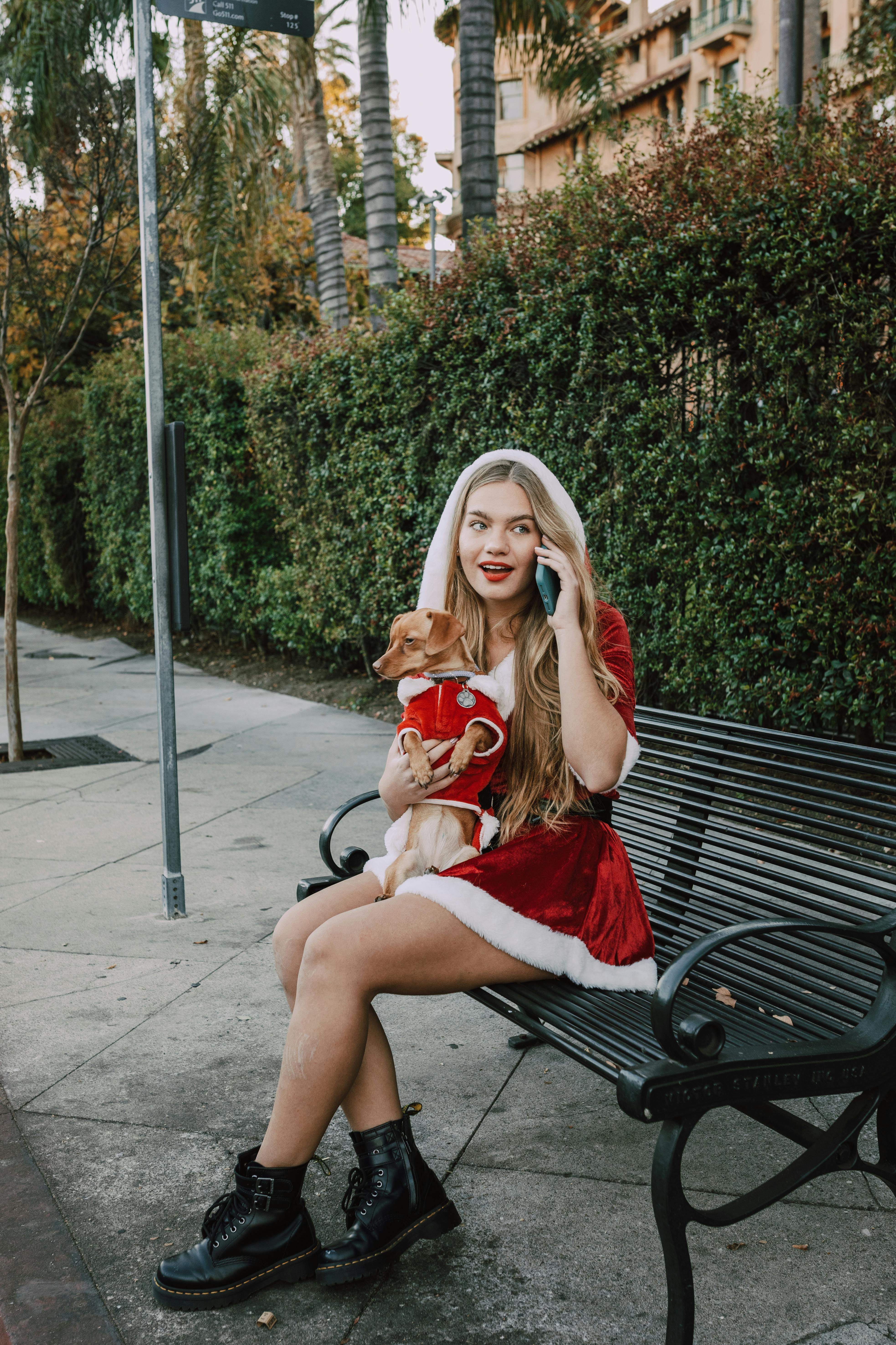 woman in red dress sitting on black metal bench holding brown dog