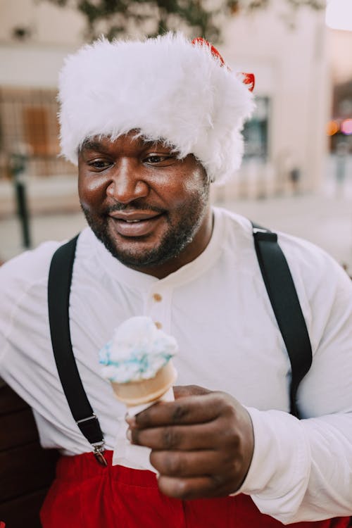Man Wearing Santa Hat is Holding a Ice Cream