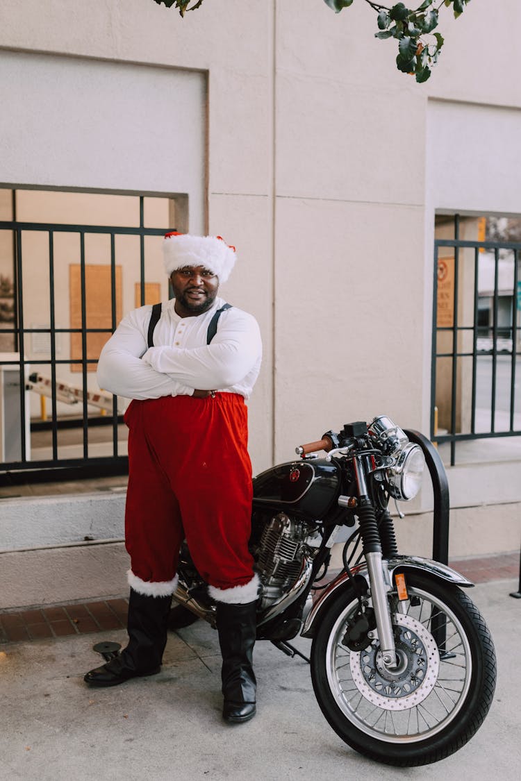 A Man In Santa Claus Costume Beside Black Motorcycle