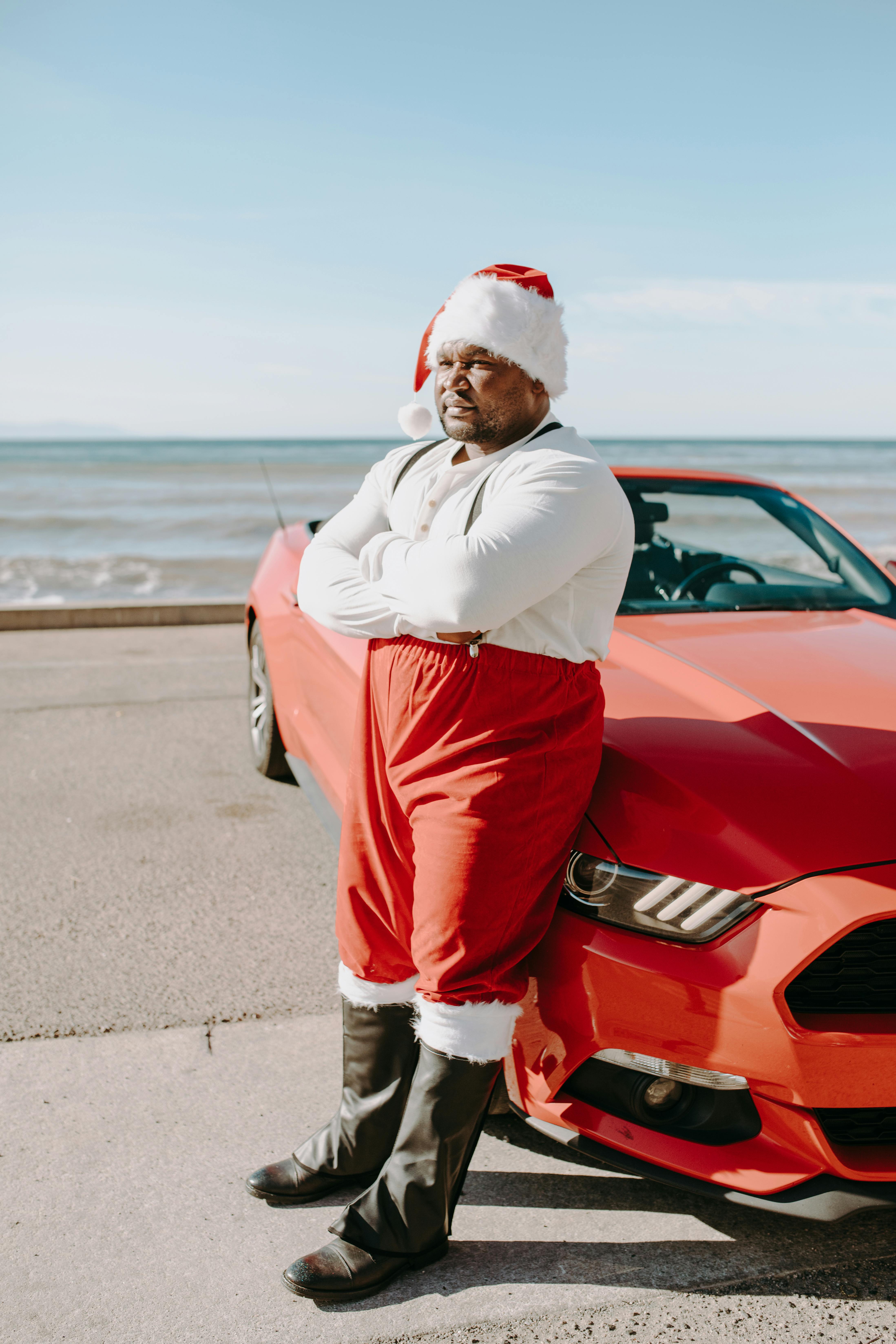 man in white dress shirt and red pants leaning on red car