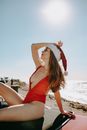 Woman in Red Bikini Sitting on Beach Shore