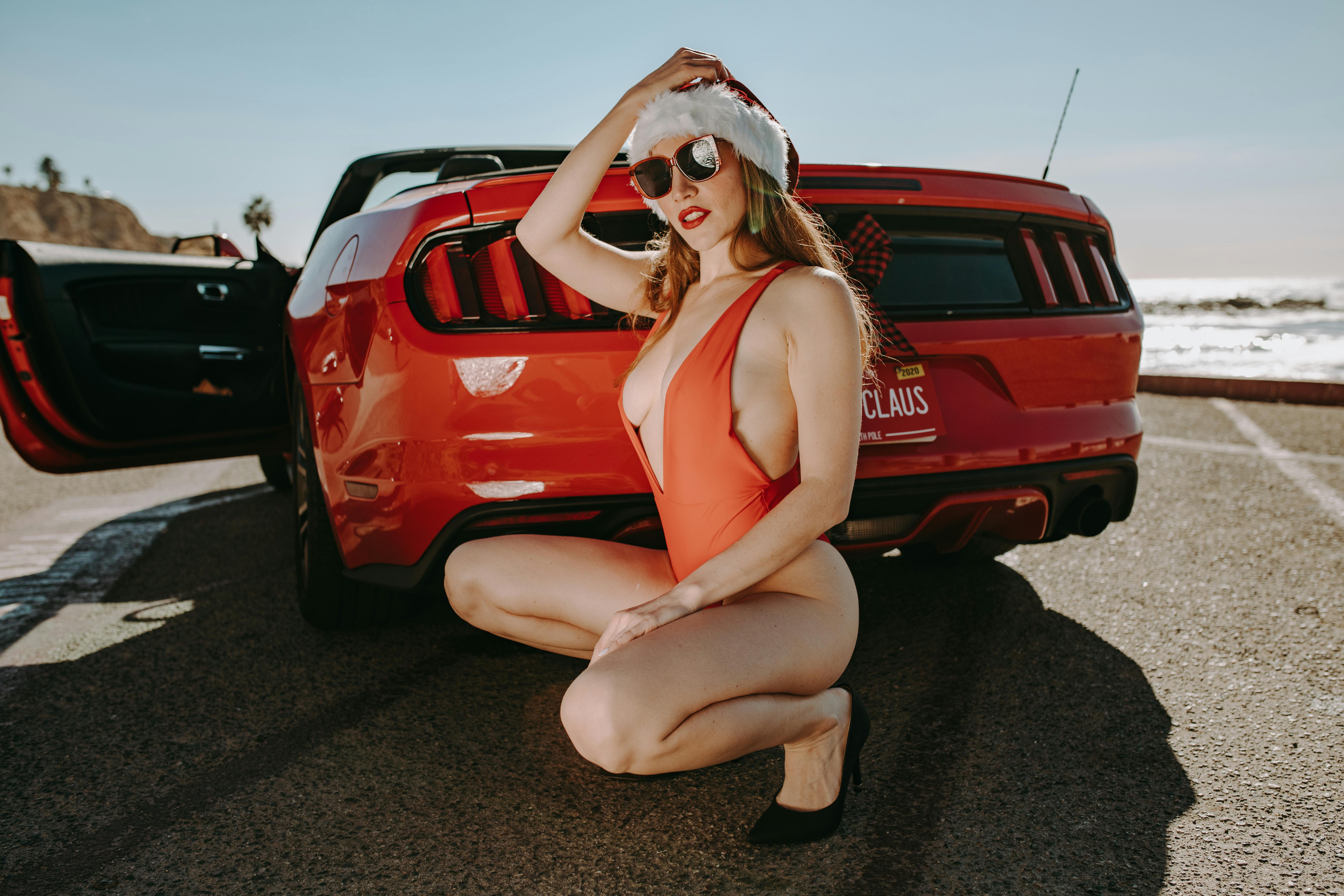 woman in red tank top and white mask sitting on red car