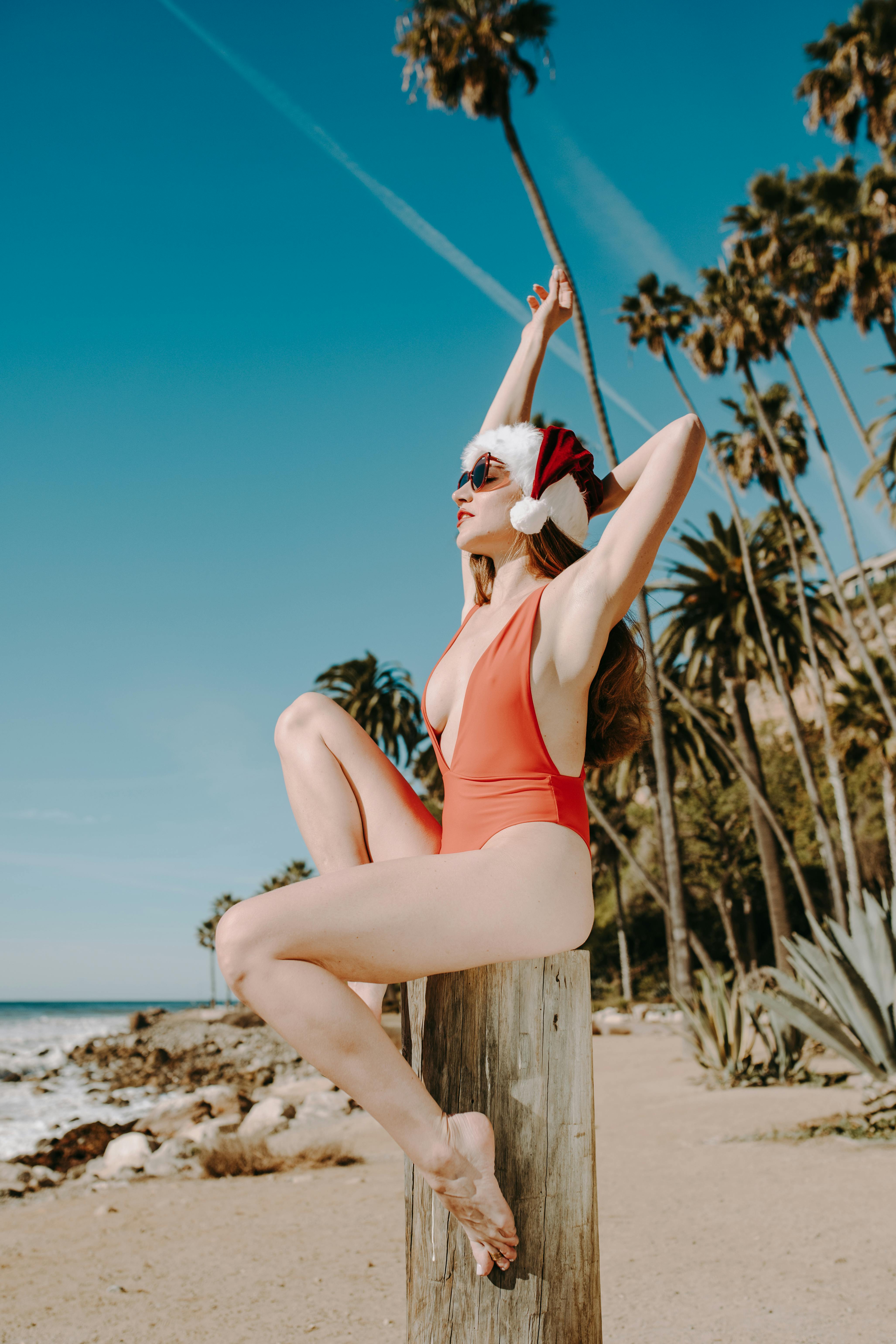 woman in red bikini sitting on brown wooden post