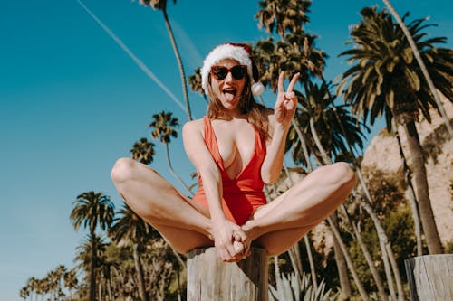 Woman in Red Tank Top and Black Sunglasses Sitting on Brown Wooden Log