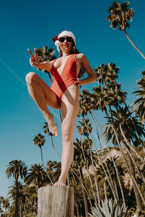 Free Woman in Red Swimsuit Standing on Brown Tree Trunk Stock Photo