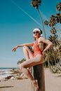 Woman in Red Bikini Sitting on Brown Wooden Log