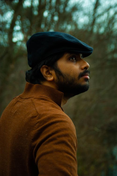 Free Man with a cap in an autumn forest, looking contemplative and serene. Stock Photo