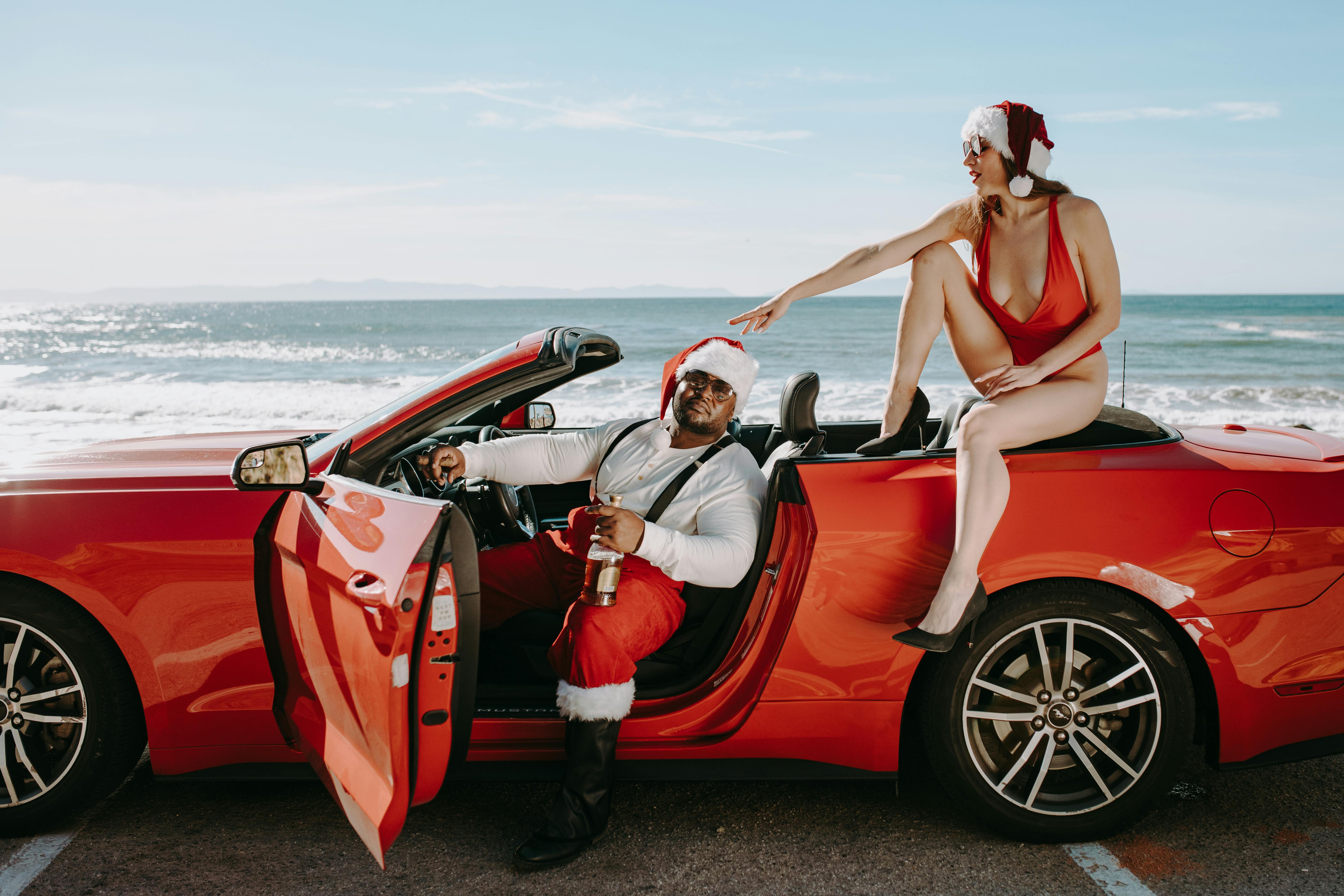 woman in red bikini sitting on red convertible car