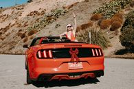 Woman in White Tank Top Sitting on Red Car