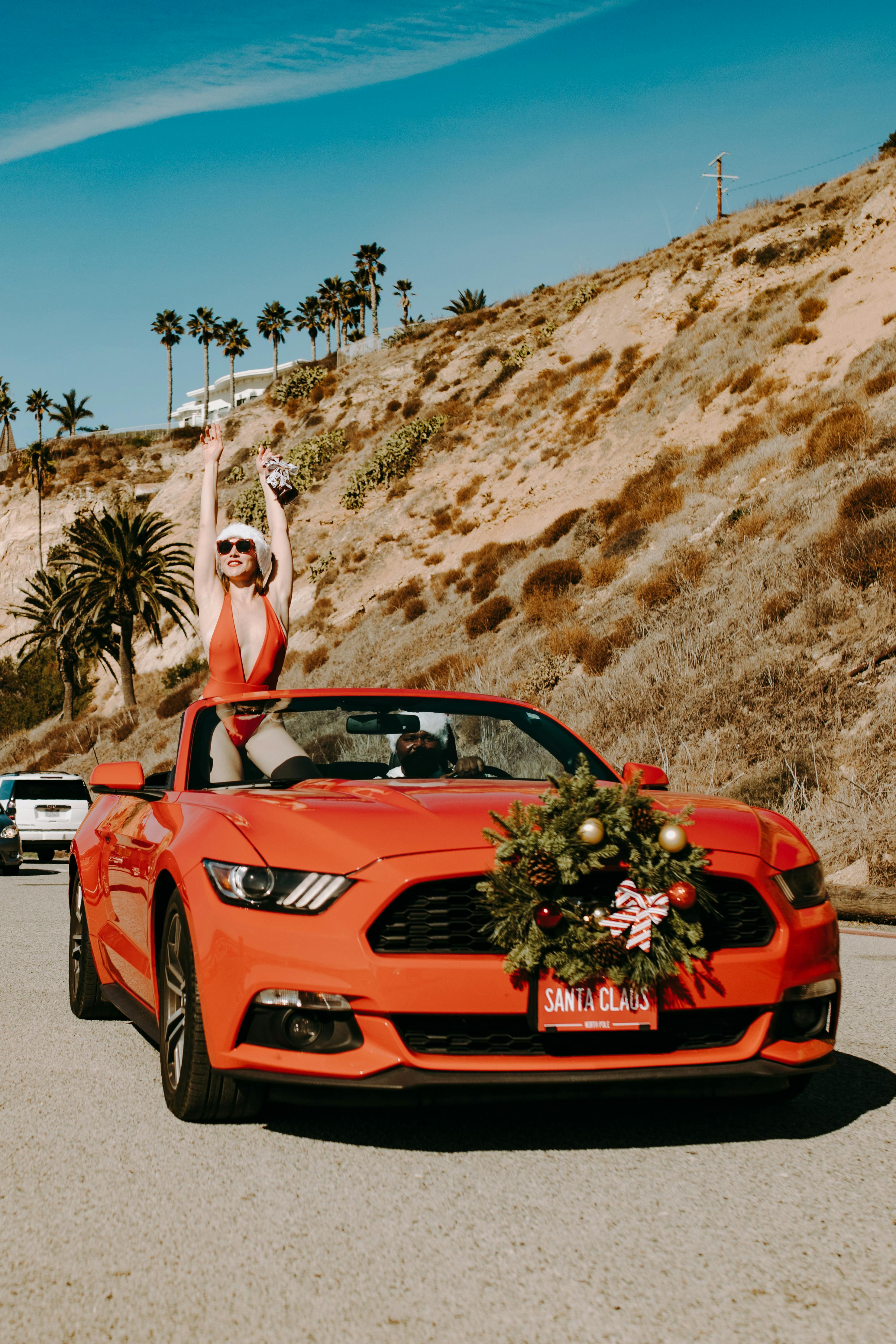 woman in white tank top sitting on red ferrari car