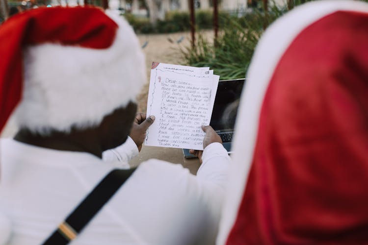 Man In Red Santa Outfit Reading A Message On Paper