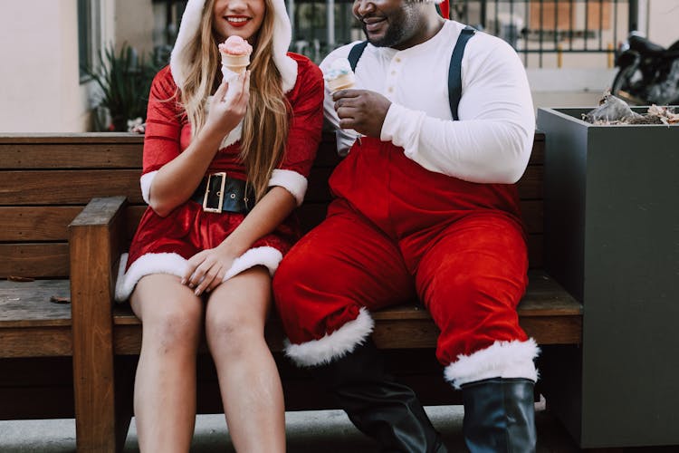 Cropped Photo Of Man And Woman In Santa Outfits Eating Ice Cream