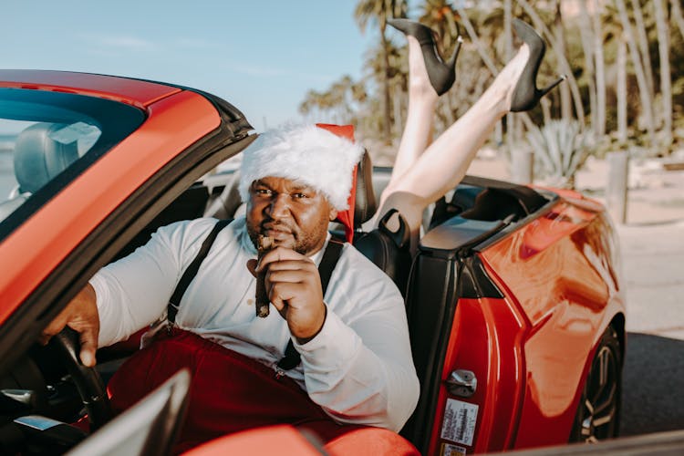 Man In Santa Outfit Sitting Inside A Red Car