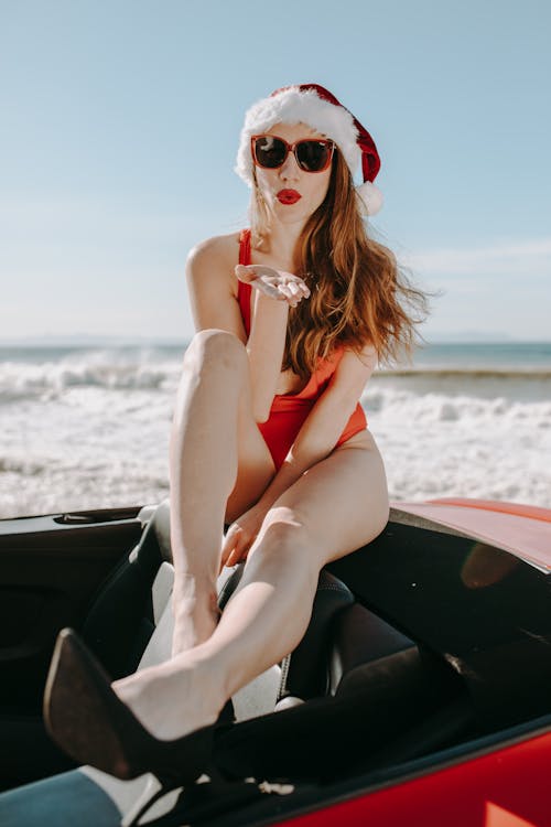 Woman in Red Bikini With Santa Hat Sitting on A Convertible Car