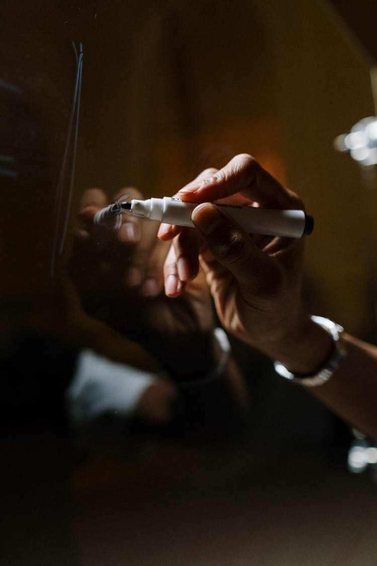 Person Using Black Marker Writing On Glass Board 