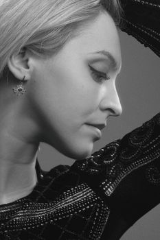 Side profile of a woman with delicate earrings in black and white.