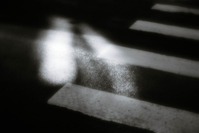 Artistic capture of a zebra crossing with reflections at night, creating an abstract view.