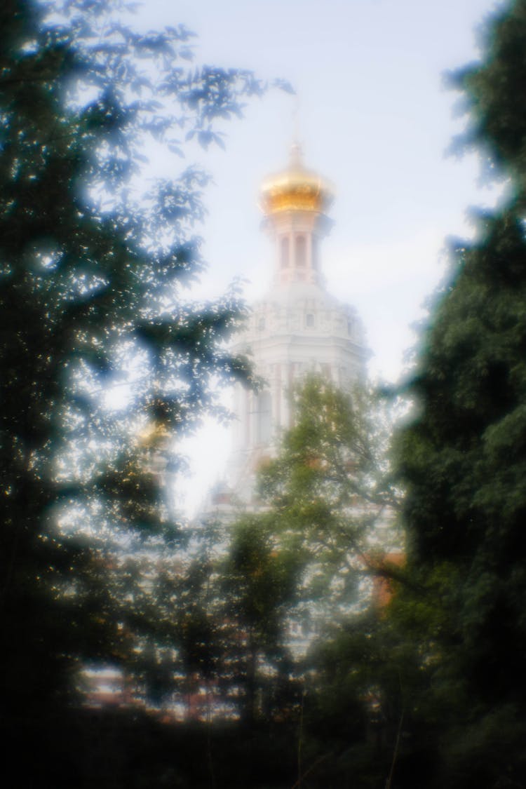 Defocused View Of A Church Tower With Trees In Foreground