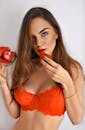 A Woman Wearing Red Bra while Holding Strawberry