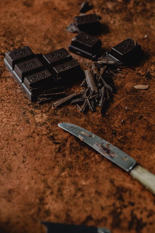 Free Dark chocolate pieces with a knife on a rustic surface in Helsinki. Stock Photo