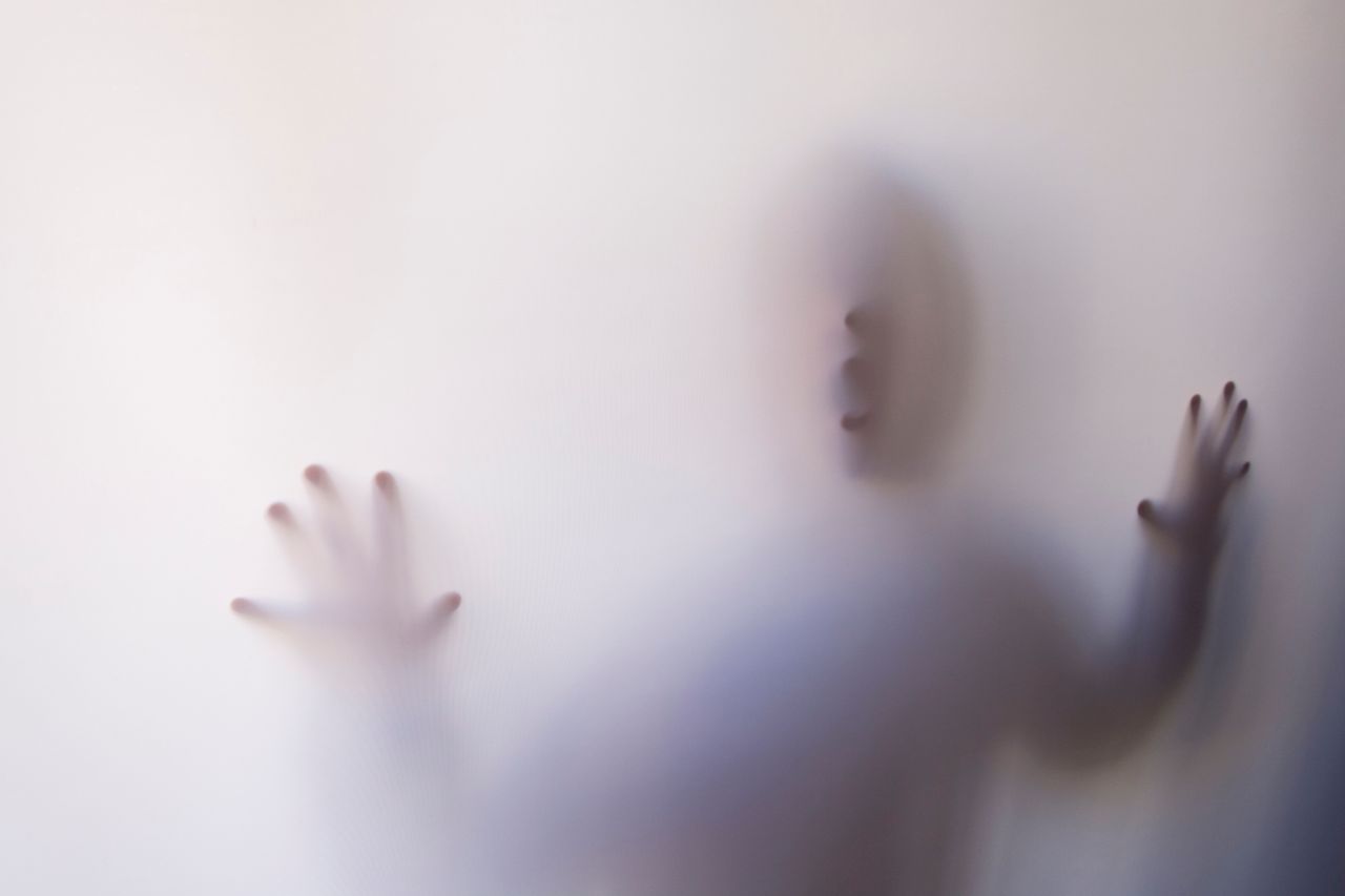 eerie silhouette of a person pressing against a white curtain creating