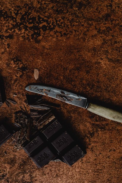 Free Close-up of dark chocolate pieces and knife on a rustic surface. Perfect for food photography and dessert themes. Stock Photo