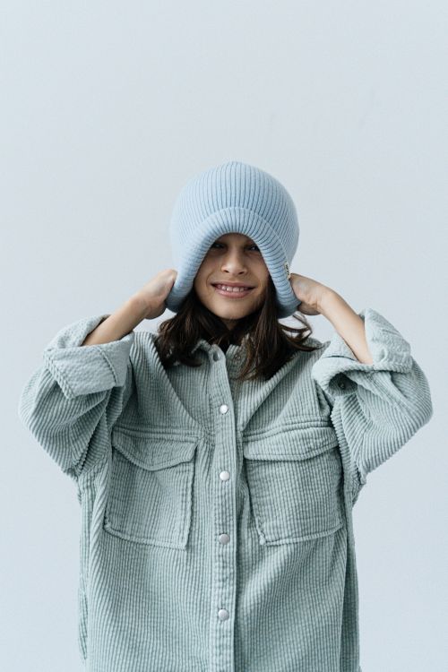 Free Cheerful girl in large jacket and hat showcasing playful fashion style. Stock Photo