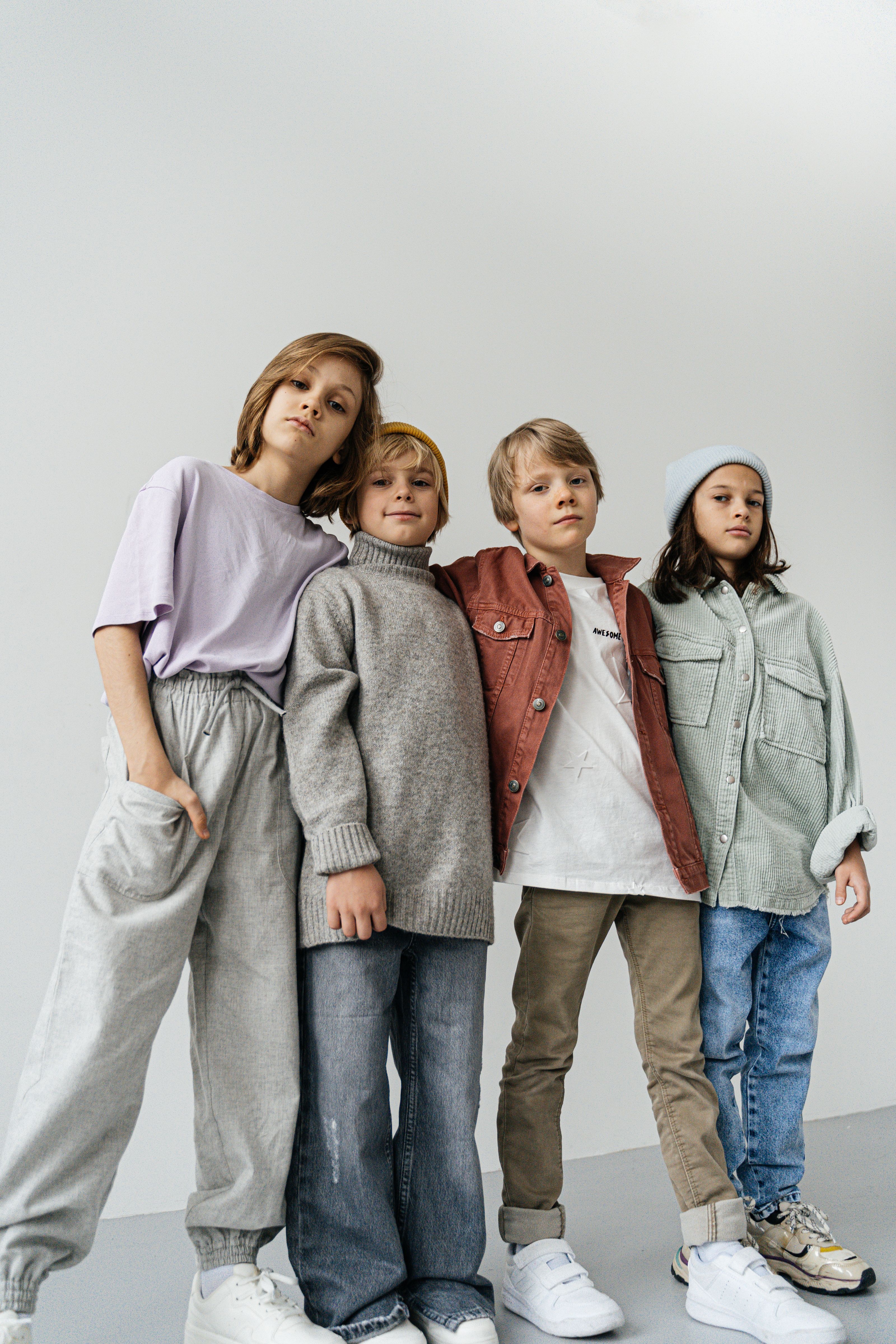 Grupo estiloso de crianças posando com roupas de inverno em ambientes internos.