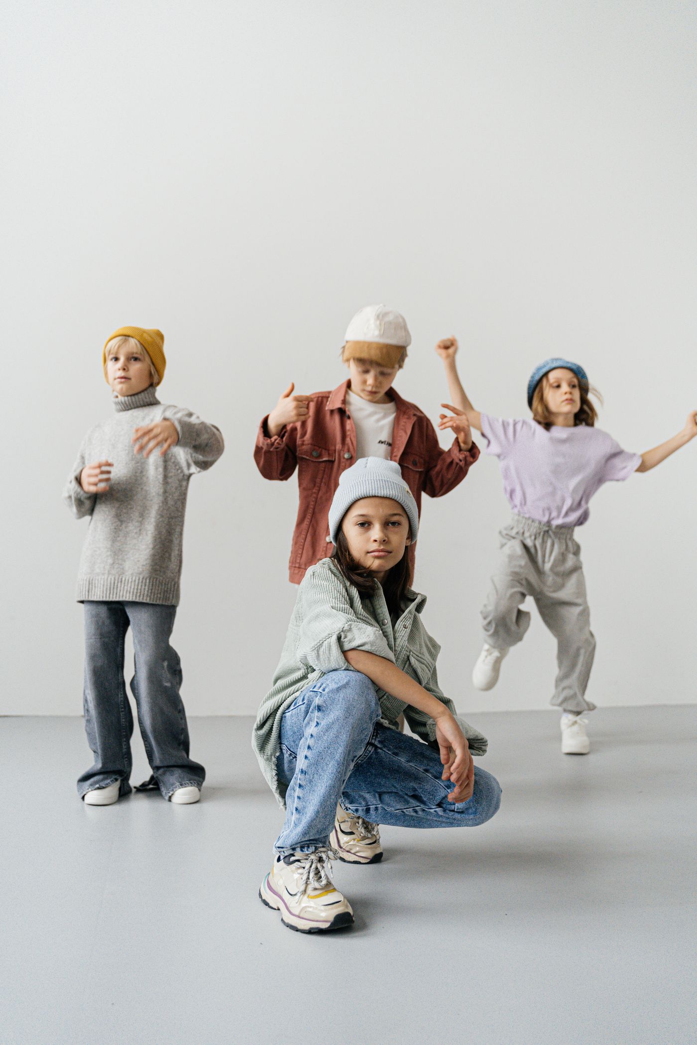 Children wearing modern casual outfits in a soft studio fashion scene