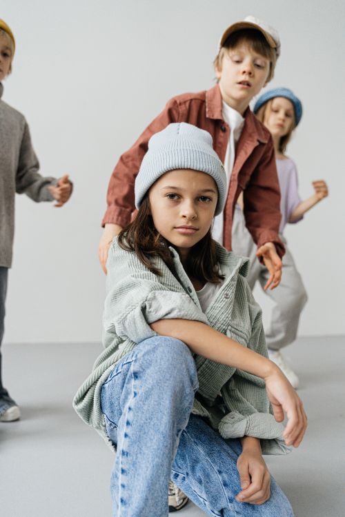 Free Four children in fashionable jackets and caps posing creatively against a white background. Stock Photo