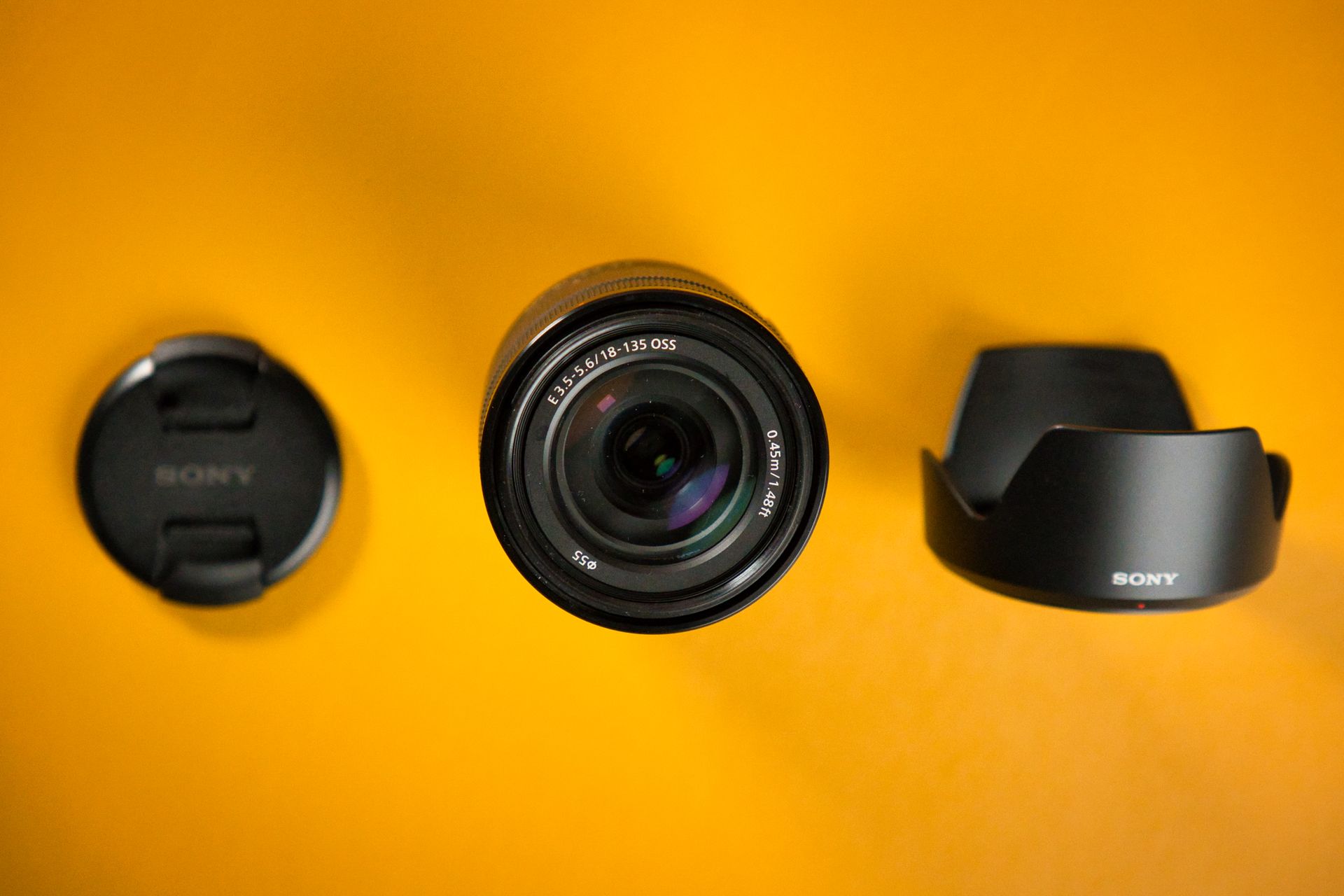 Top view of Sony camera lens set on a vivid yellow background, ideal for tech and photography content.