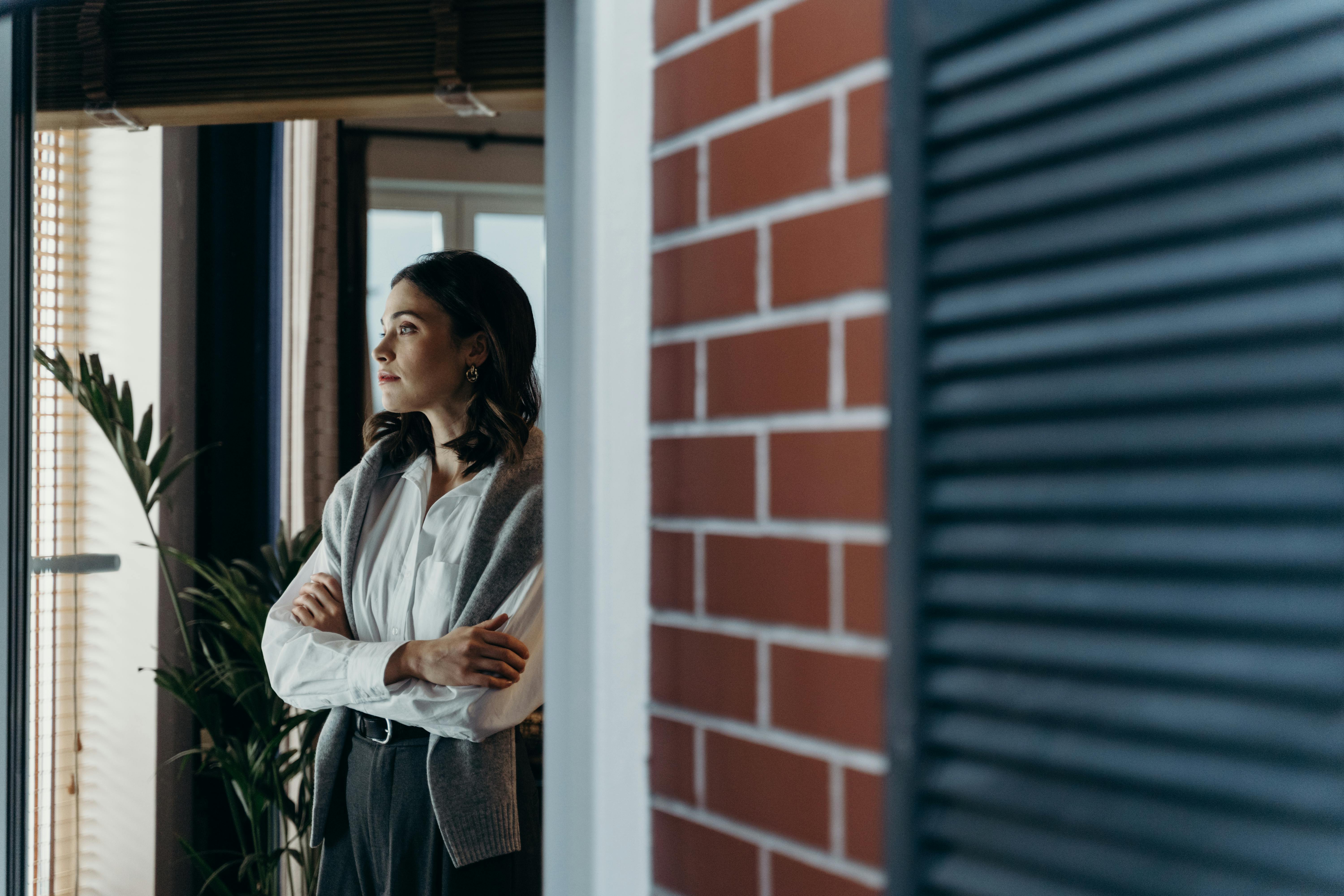 a person looking thoughtfully out a window, representing self-reflection. - Inpatient rehab Costa Mesa