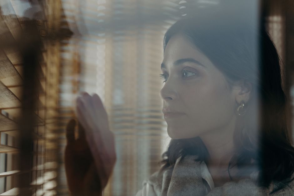 Mulher pensativa observando pela janela, em clima contemplativo e tranquilo