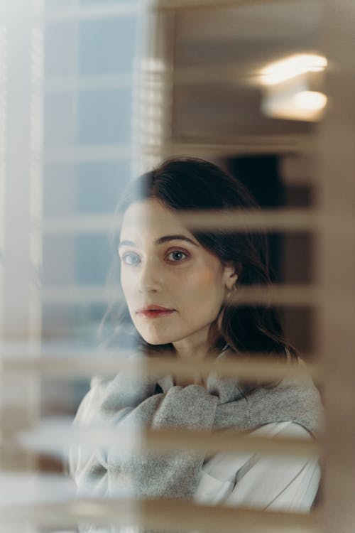 Woman in White Shirt with Gray Jacket Looking Through a Window