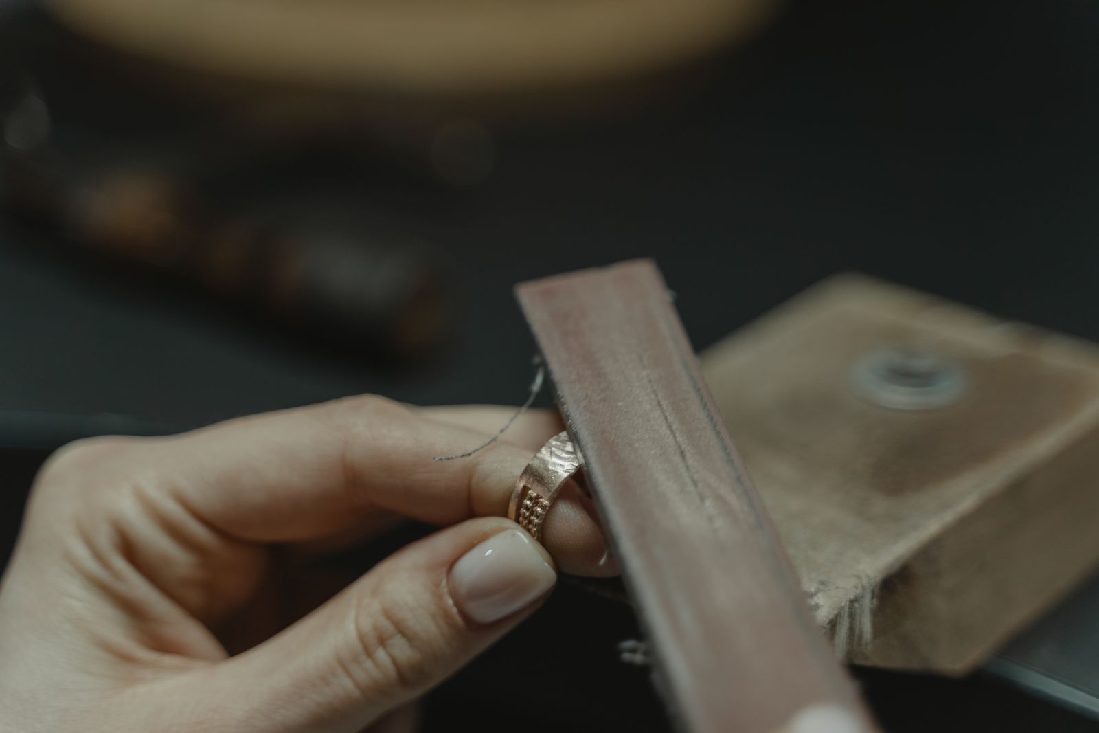 A goldsmith's hands working a ring at the bench