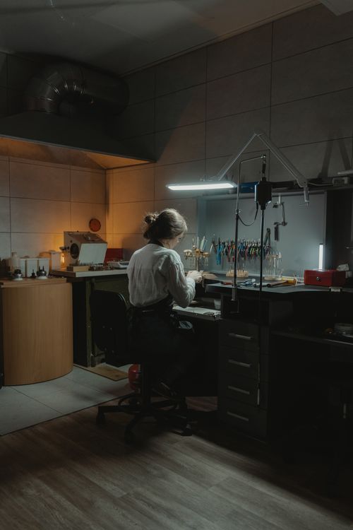Free A skilled jeweler crafting jewelry in a dimly lit workshop, surrounded by tools and equipment. Stock Photo