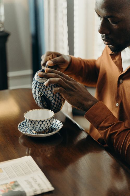 Free Man pouring tea in a delicate porcelain cup, depicting a serene indoor setting. Stock Photo