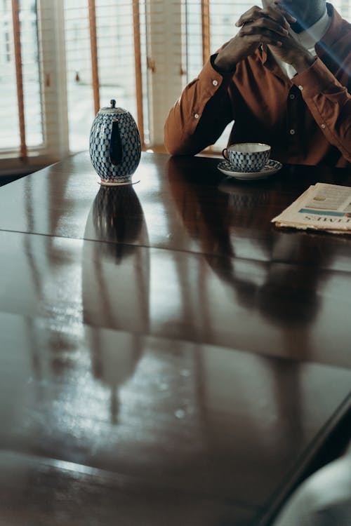 A Person Sitting at a Table with an Elegant Cup and Teapot