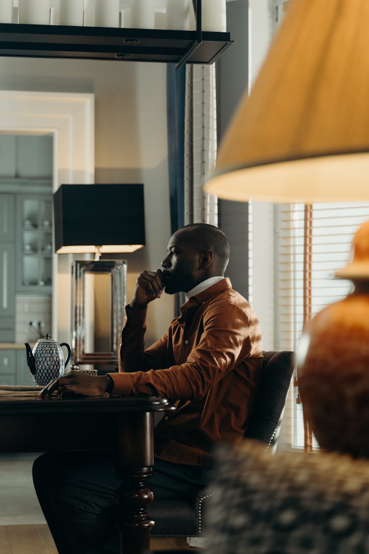 Man Sitting At The Table With A Teapot