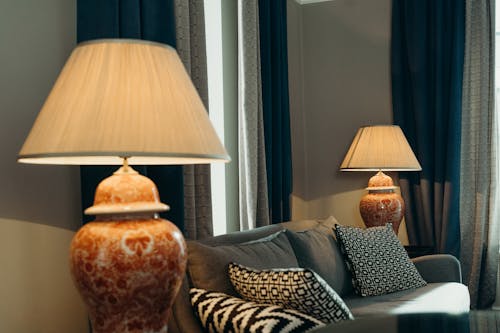A Couch with Pillows Between Lamps Near the Curtains