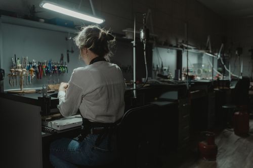 Free Woman artisan crafting jewelry in a focused workspace with tools. Stock Photo