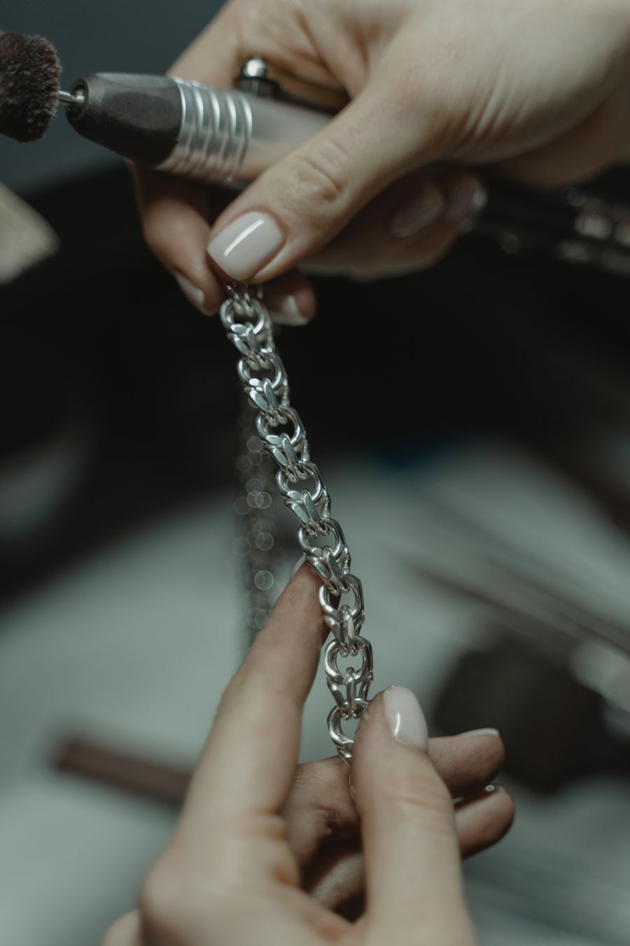 Jeweler polishing a silver chain with a tool