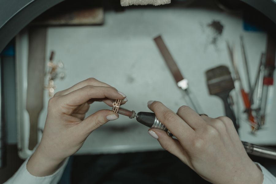 Hands using a rotary tool to polish a ring