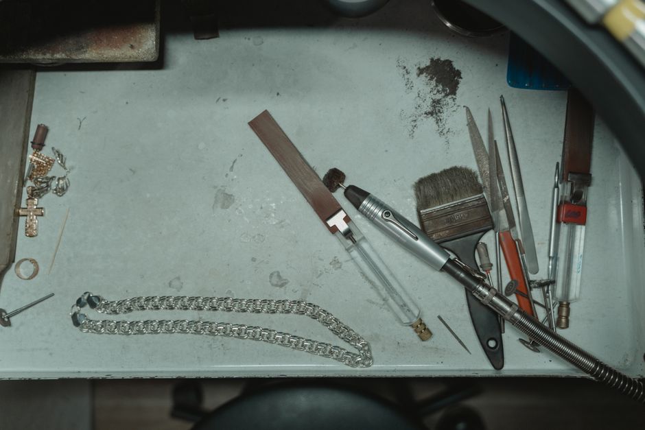 workbench with broken necklace chains and loose gemstones workbench with broken necklace chains and loose gemstones