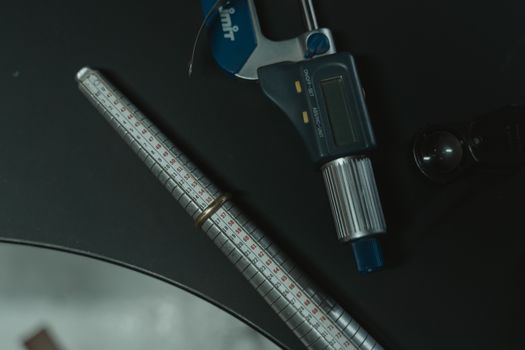 Close-up of a jeweler's tools including a ring sizer and digital caliper for precision craftsmanship.