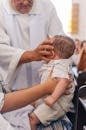 Elderly priest stroking baby during baptism ceremony