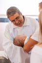 Smiling priest wiping baby head during baptism ceremony