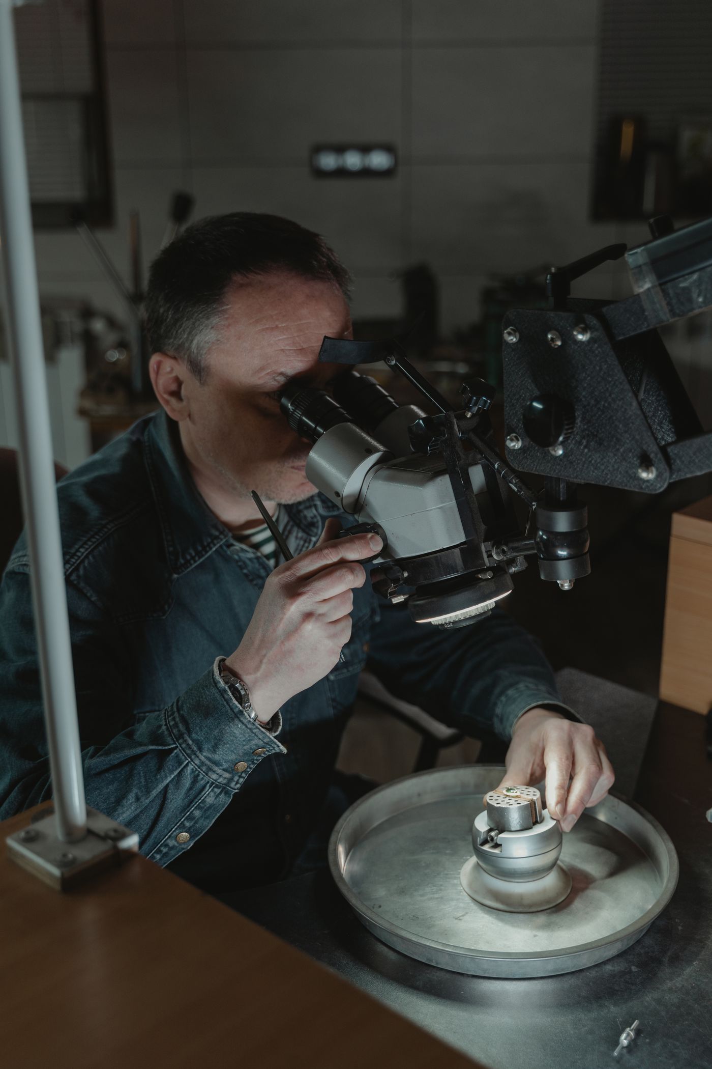 Joyero examinando una pieza con el microscopio en el taller