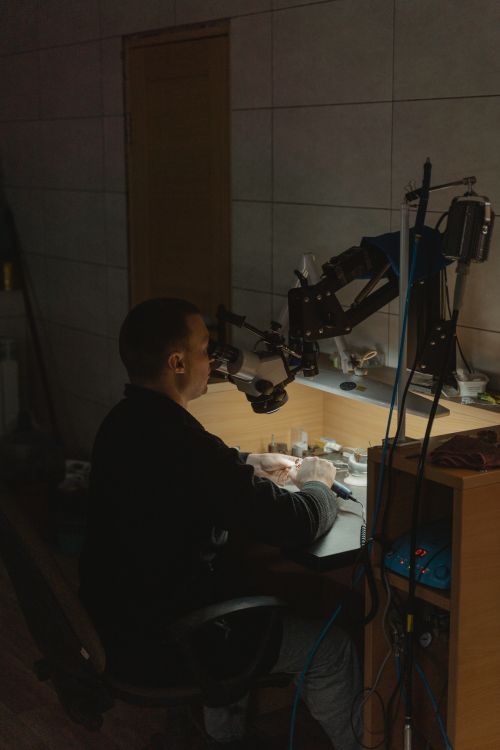 Free Craftsman working at jewelry workstation with precision tools under focused lighting. Stock Photo