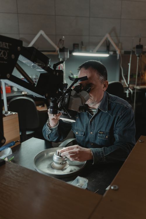 Free Experienced jeweler using magnifying equipment in a workshop for precision craftsmanship. Stock Photo